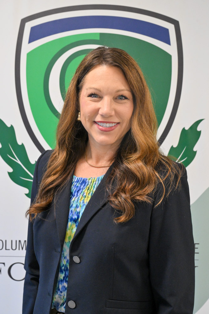 A person poses and smiles for a photo with a professional background behind them.