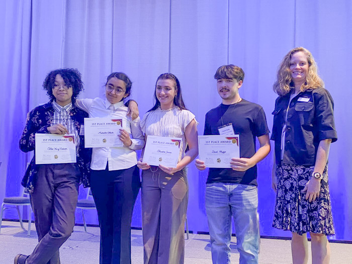 A group of people hold up certificates and smile for a photo.