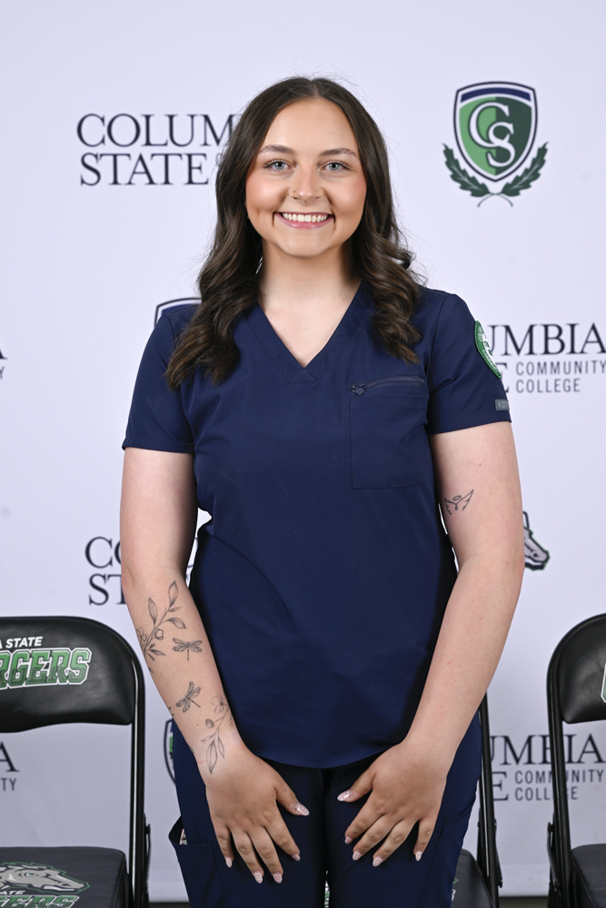 A woman stands in front of a white background.