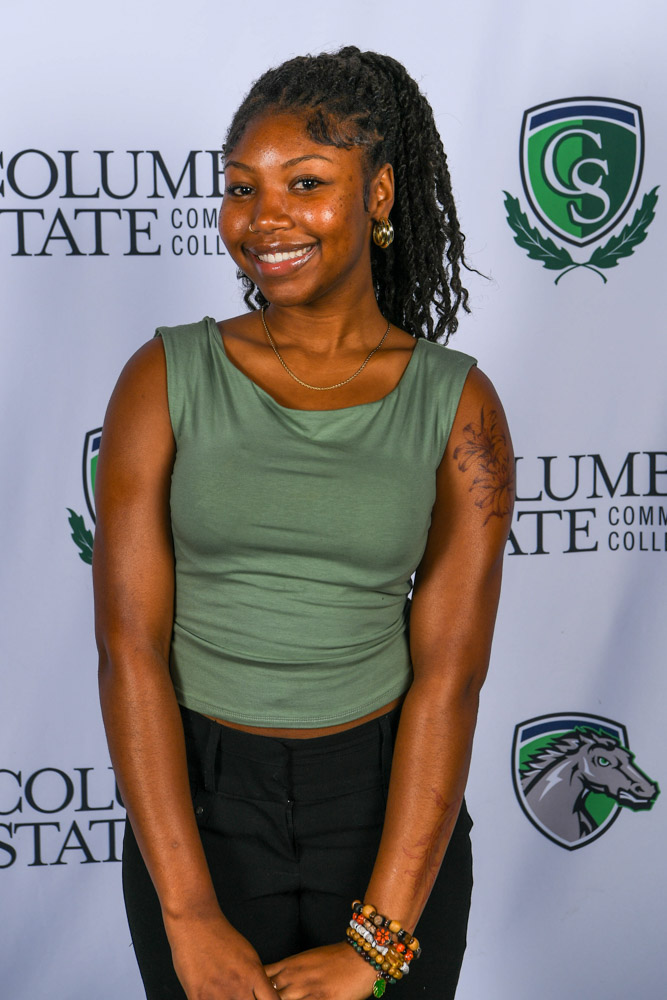 A woman stands in front of a white background.