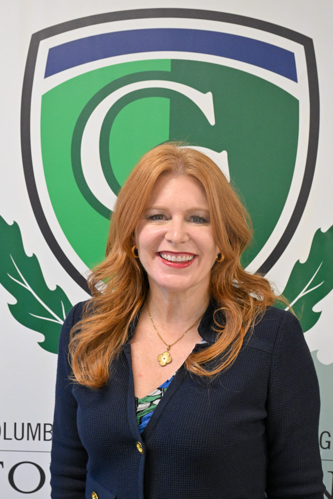A person poses for a photo in front of a professional background.