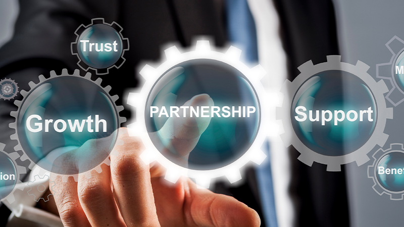 A hand touches a glowing circular interface labeled “PARTNERSHIP,” surrounded by gear-shaped icons reading “Growth,” “Trust,” and “Support” against a blurred business background.